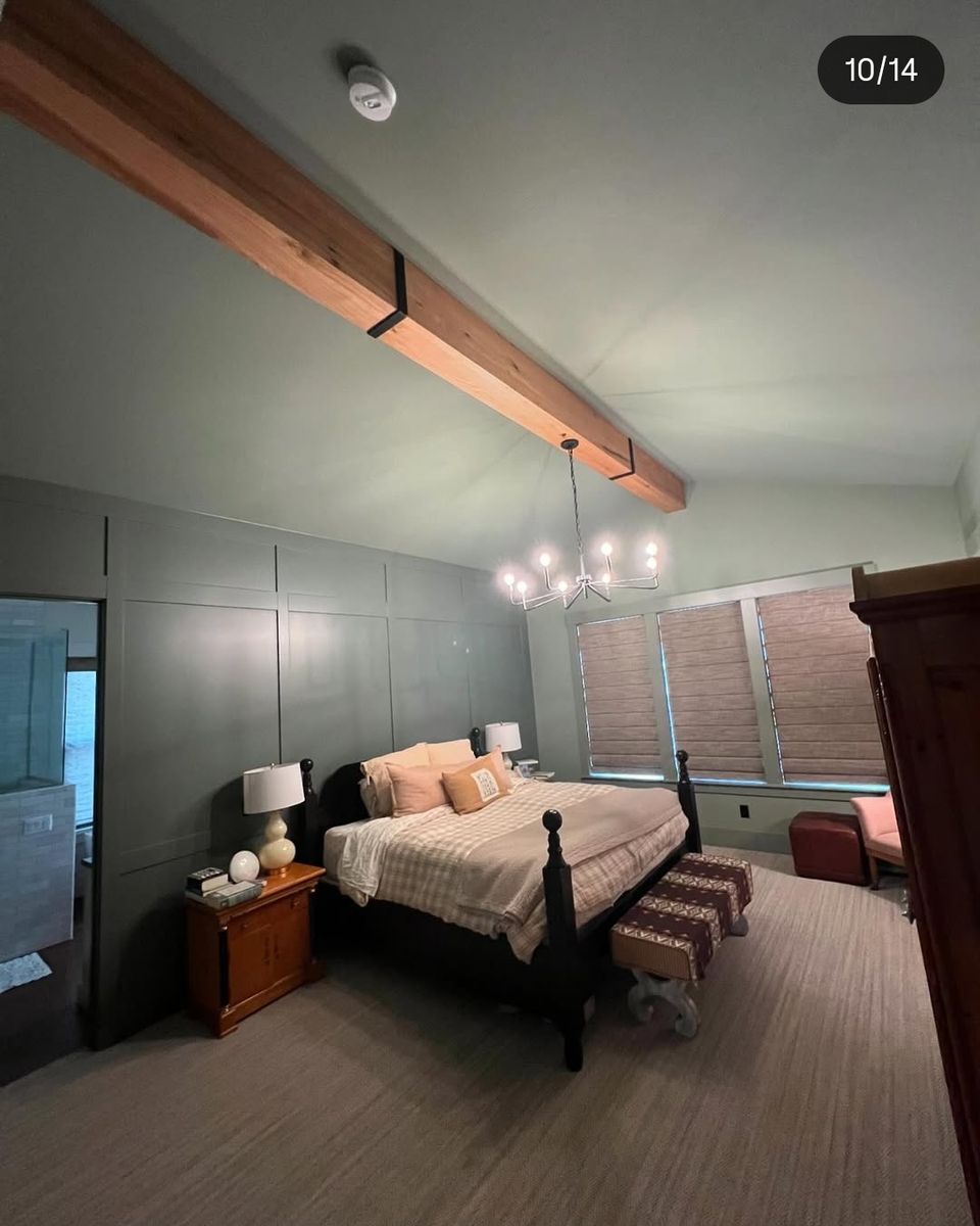 Vaulted bedroom with a single exposed beam on black straps and a panelled accent wall