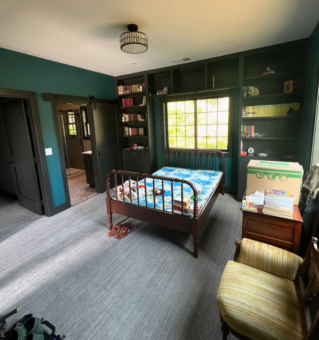 Bedroom with deep green built-in bookcases framing a window seat, and a matching sliding barn door