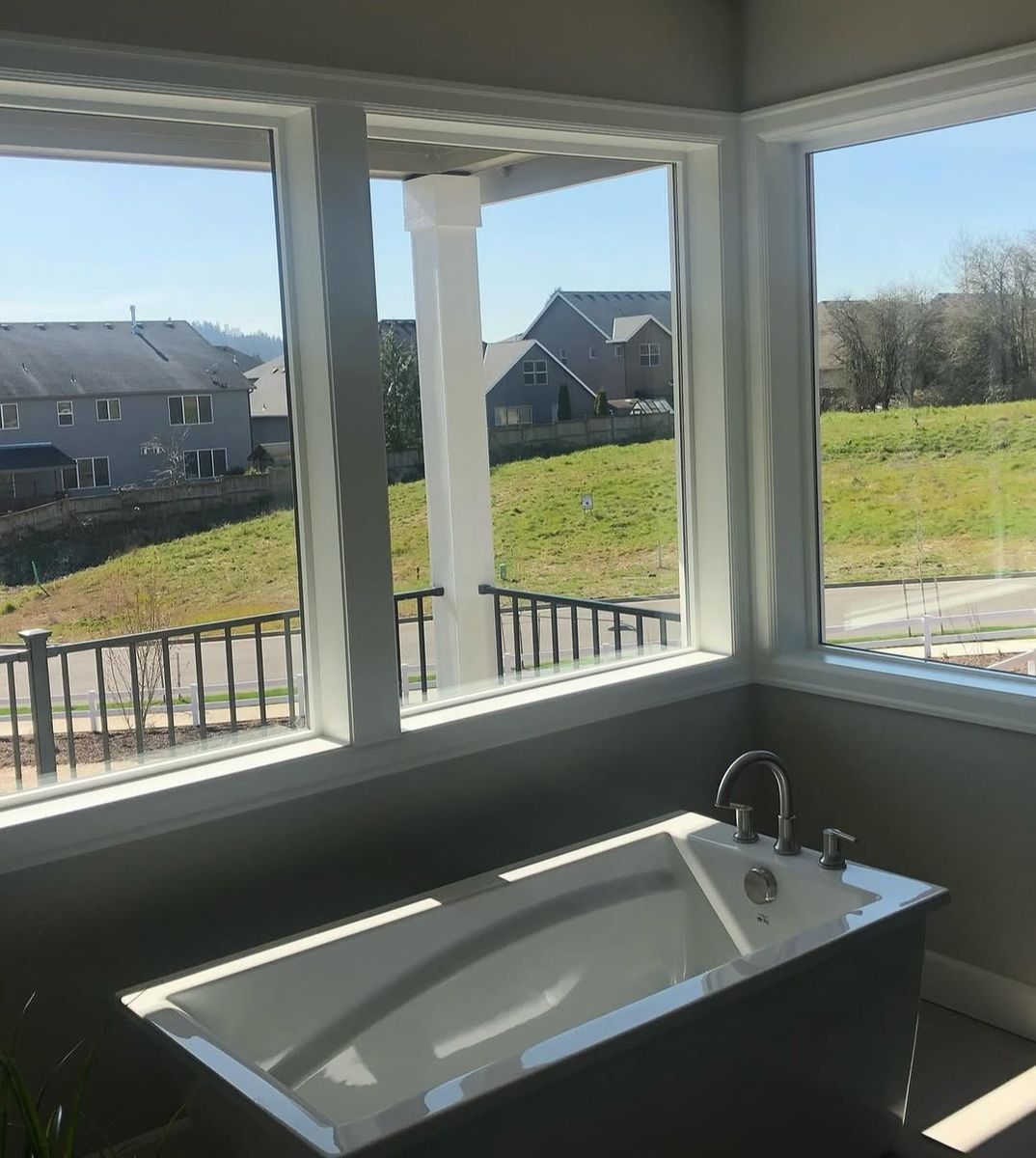 Soaking tub set into a corner of windows with wide painted casing and a deep sill