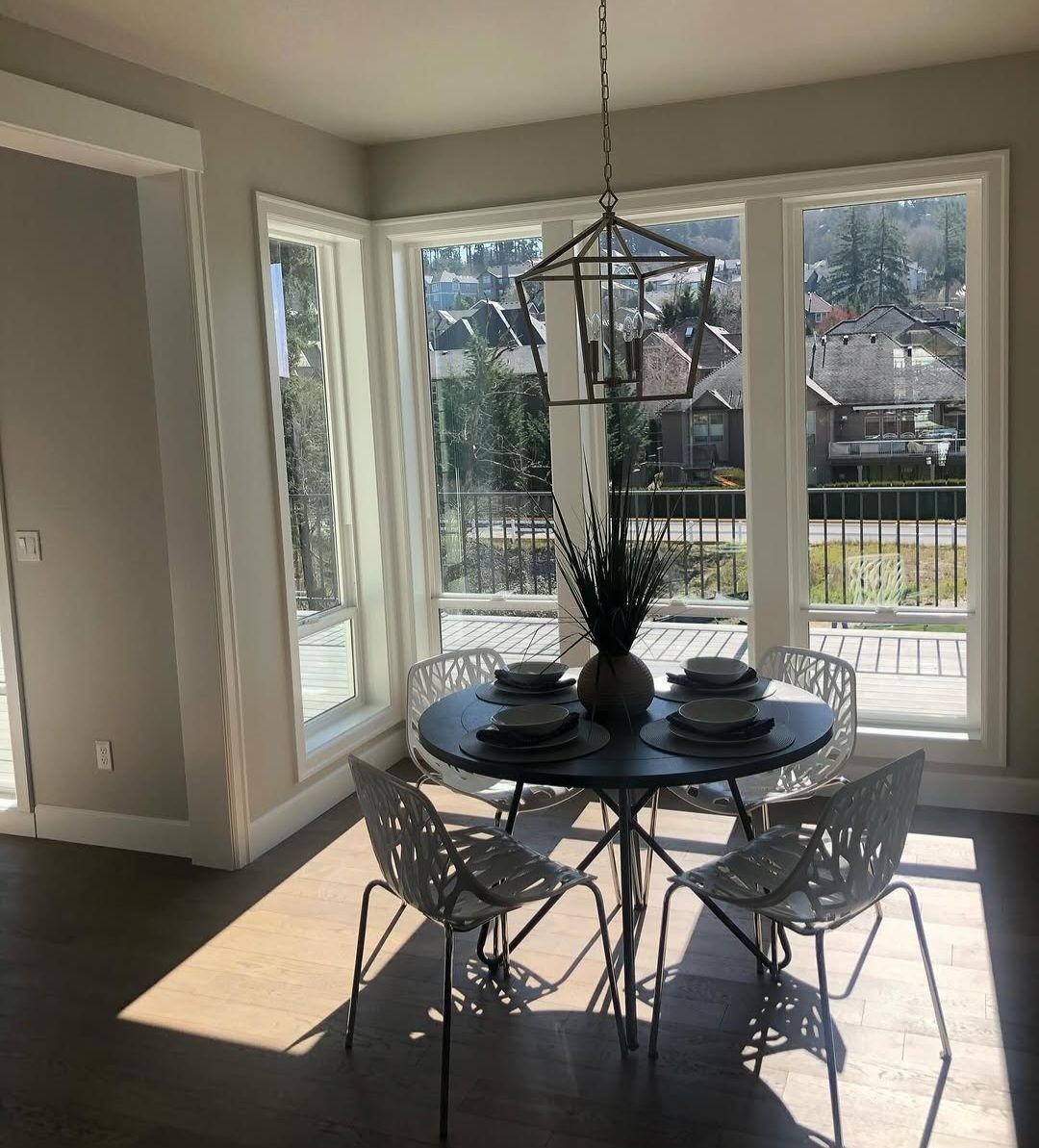 Breakfast nook wrapped in corner windows with wide painted casing, under a lantern pendant