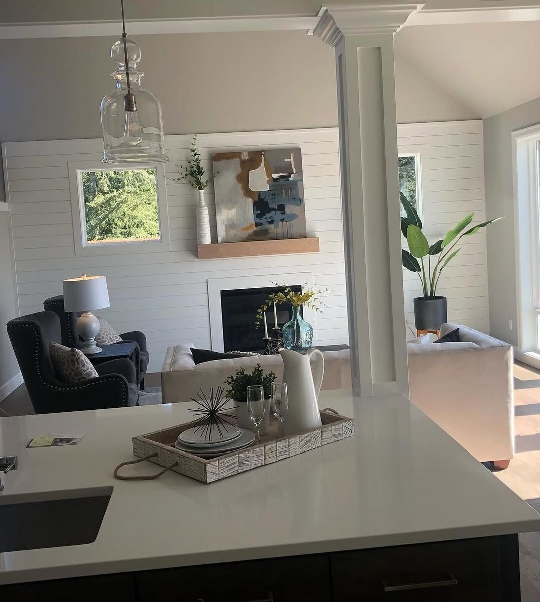 View across a kitchen island to the shiplap fireplace wall, framed by a tapered craftsman column