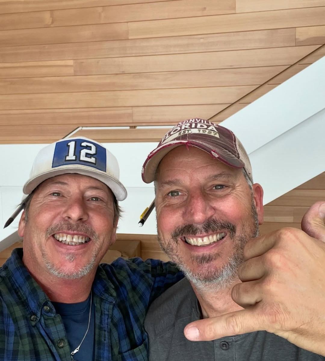 Mark Nelsen on the right and his brother Mitch on a jobsite, under a cedar-clad vaulted ceiling they installed